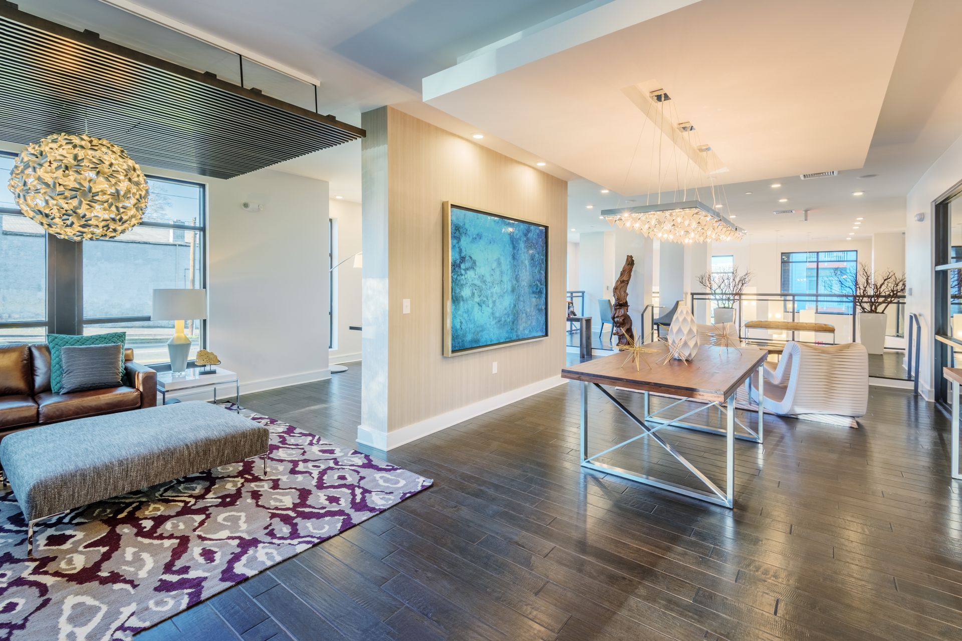Spacious modern living space with dark wood floors, artwork, and various light fixtures.