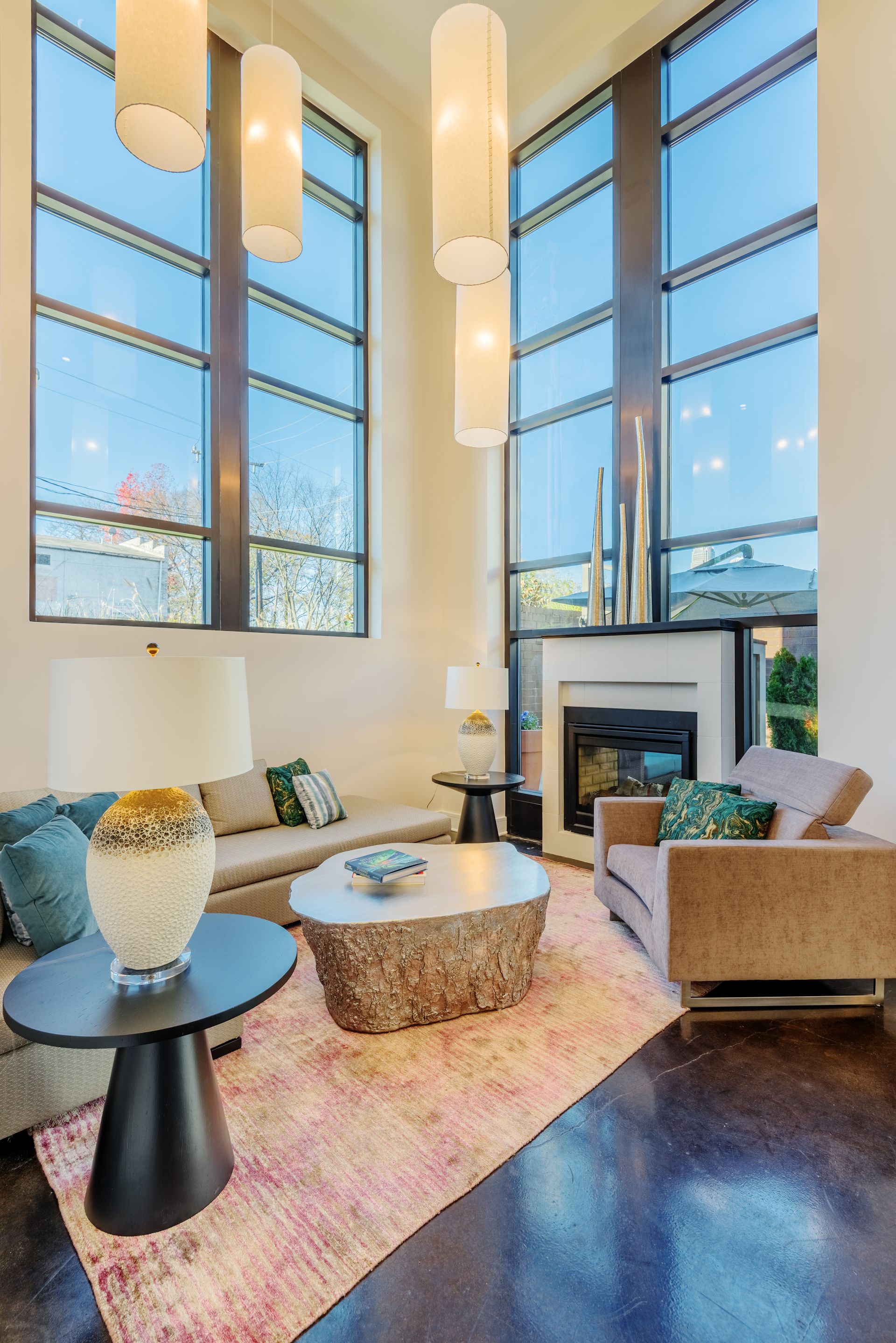 Living room with tall windows, fireplace, modern furniture, and a pink rug.
