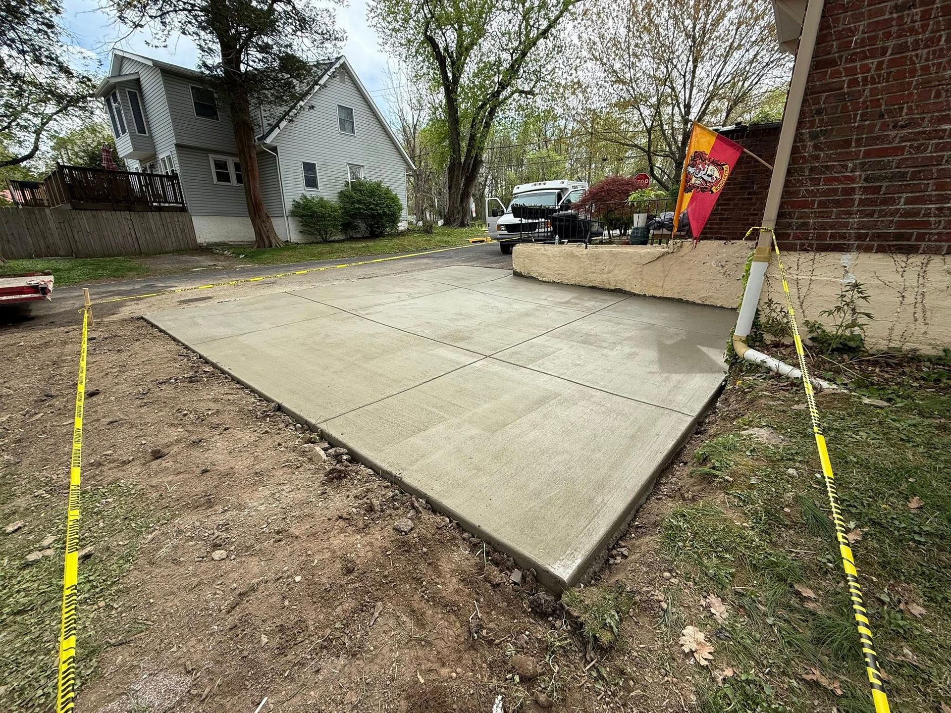 New concrete driveway and walkway beside a house, with construction markings and dirt edges