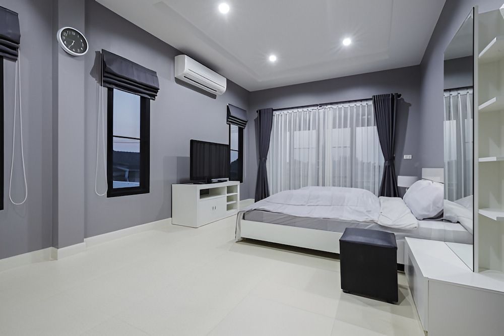 A Bedroom With A Bed, Television, Dresser And Mirror — Mason's Air Conditioning Pty Ltd in Drayton, QLD