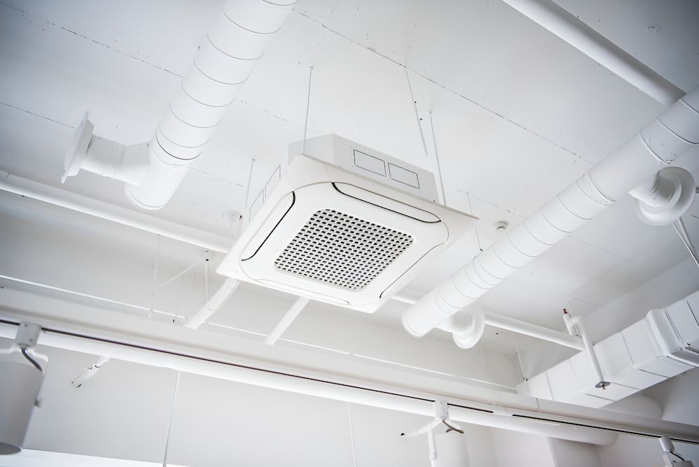 A White Air Conditioner Is Hanging From The Ceiling Of A Room — Mason's Air Conditioning Pty Ltd in Drayton, QLD