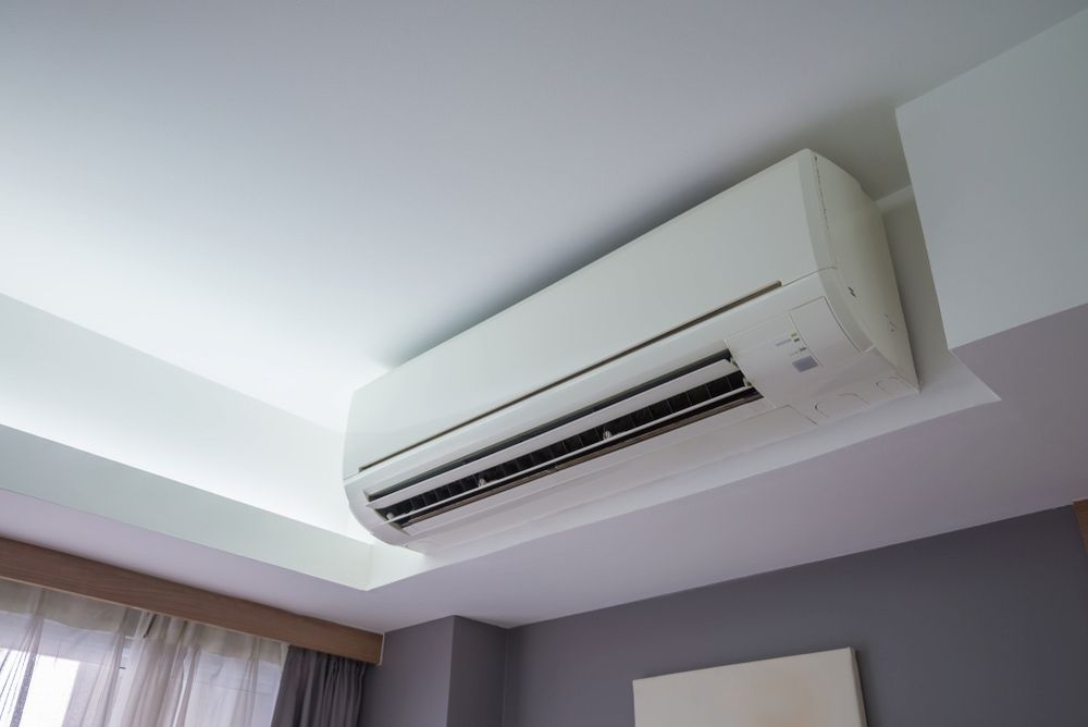 A White Air Conditioner Is Hanging From The Ceiling In A Bedroom — Mason's Air Conditioning Pty Ltd in Drayton, QLD