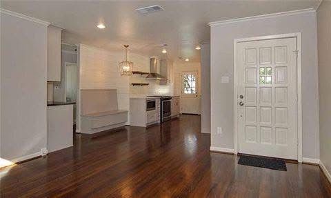 Interior shot: Open-plan kitchen and living area with hardwood floors, light gray walls, and white door.