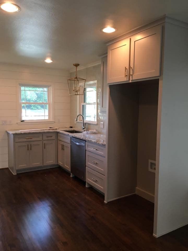 Kitchen with light gray cabinets, stainless steel appliances, and dark wood floor.