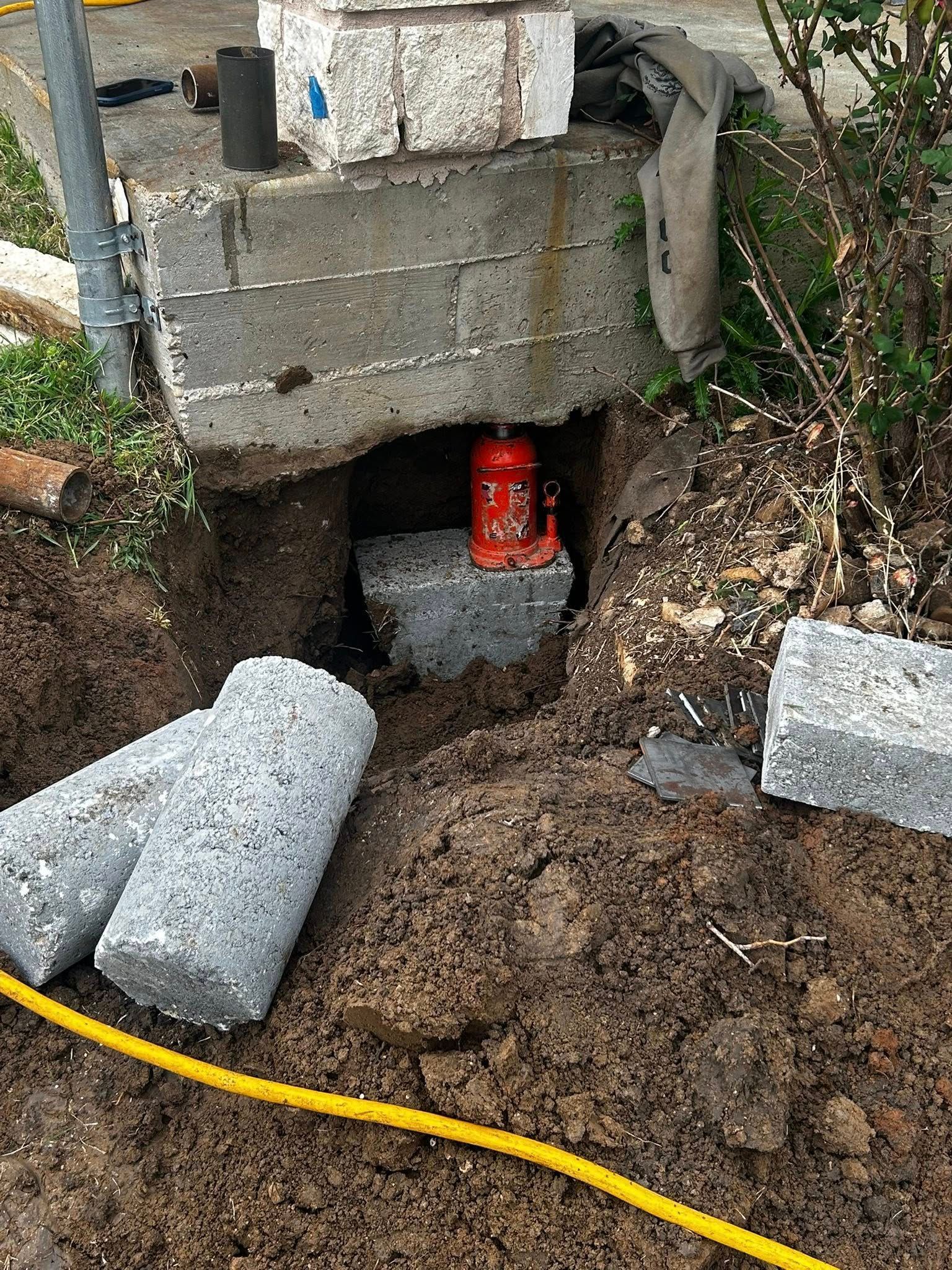 Construction site: jack lifts a concrete block. Other blocks, earth, and tools surround.
