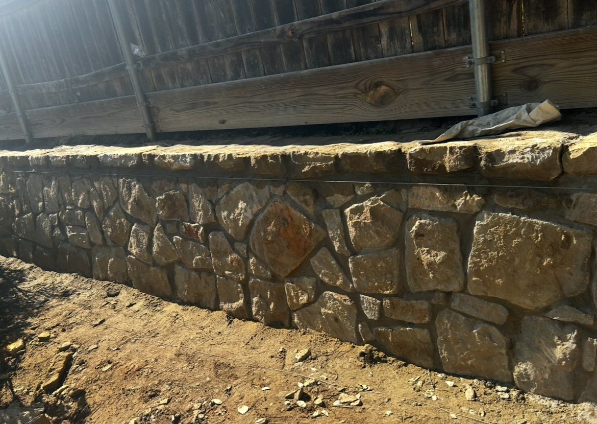 Stone wall with rough-hewn stones and dirt. Brown and tan tones.