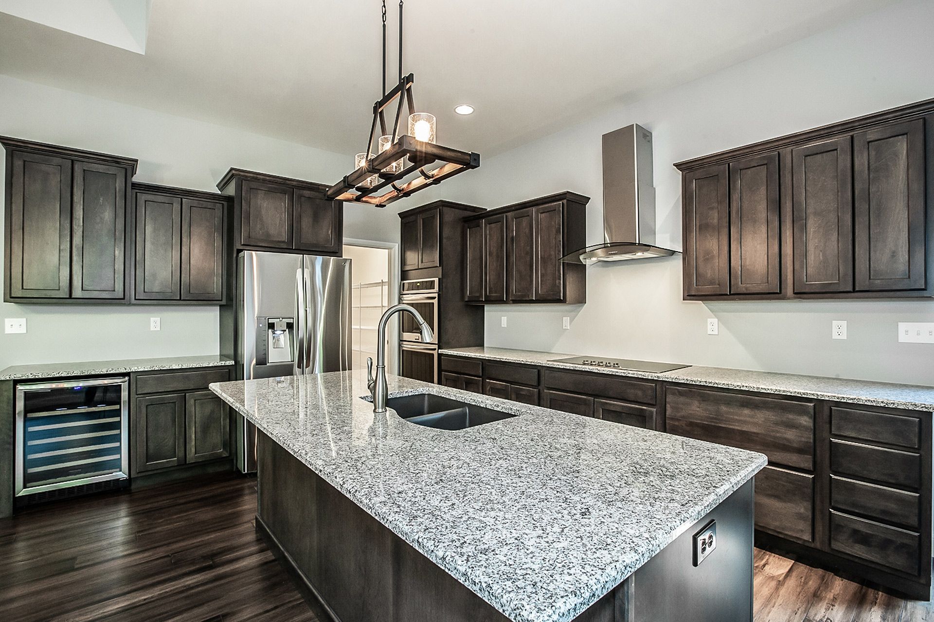 Modern kitchen with dark wood cabinets, granite island, stainless appliances, and pendant lighting