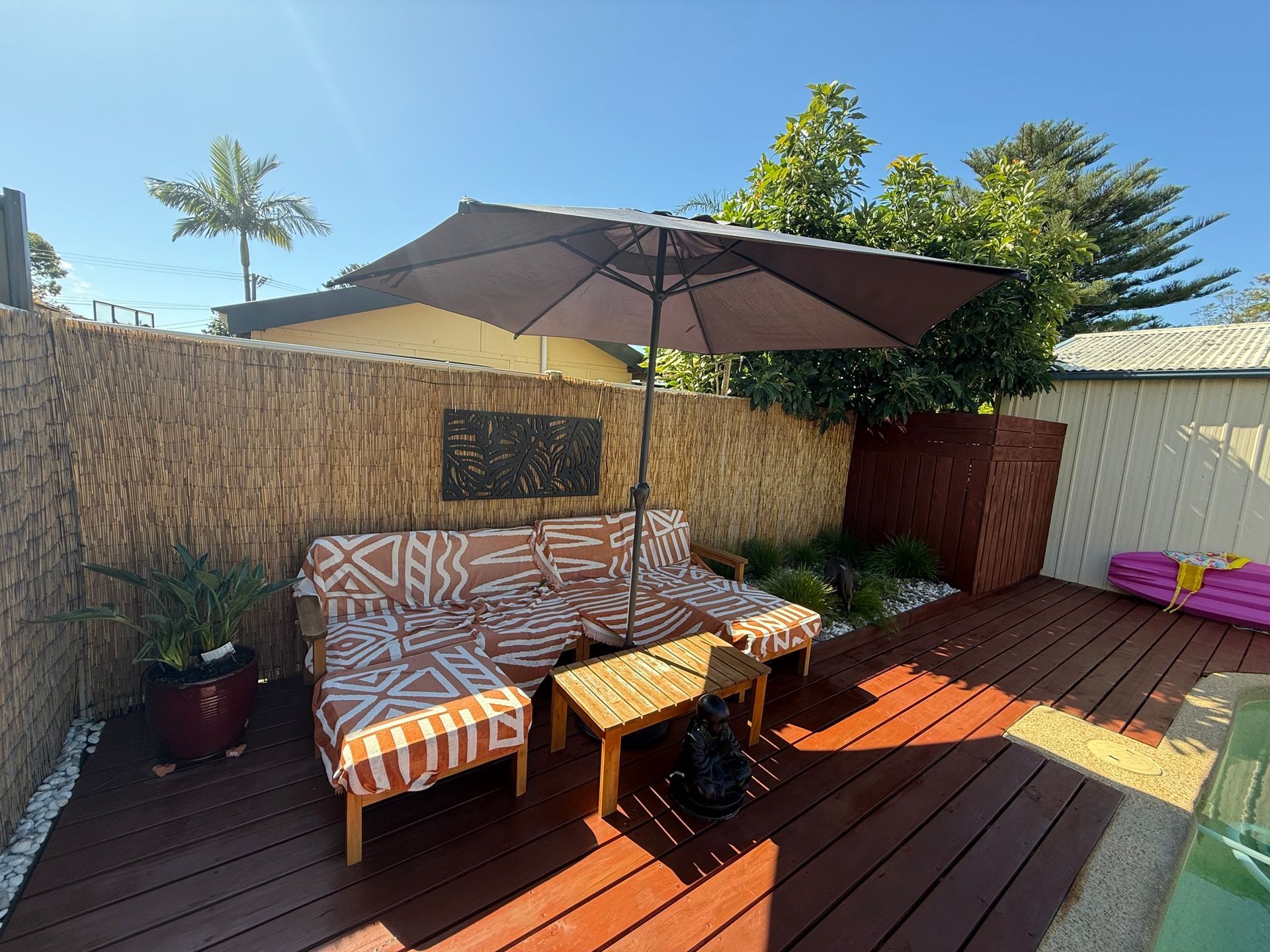 A Wooden Deck With a Couch, Table, and Umbrella — Central Coast Property Maintenance Services In Umina Beach, NSW