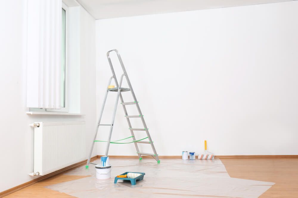 An empty room with a ladder , paint buckets , and paint rollers — Central Coast Property Maintenance Services In Umina Beach, NSW
