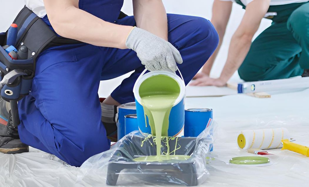 A Man is Pouring Green Paint Into a Tray — Central Coast Property Maintenance Services In Killcare, NSW
