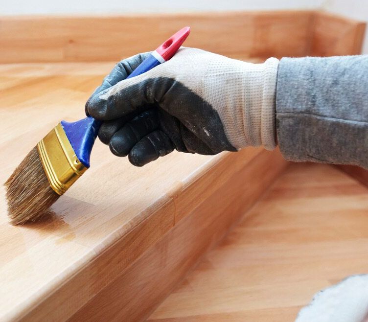 A Person is Painting a Wooden Surface With a Brush — Central Coast Property Maintenance Services In Kariong, NSW