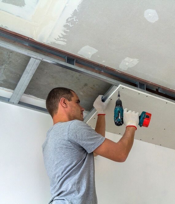 A Man is Working on a Ceiling With a Drill — Central Coast Property Maintenance Services In Umina Beach, NSW