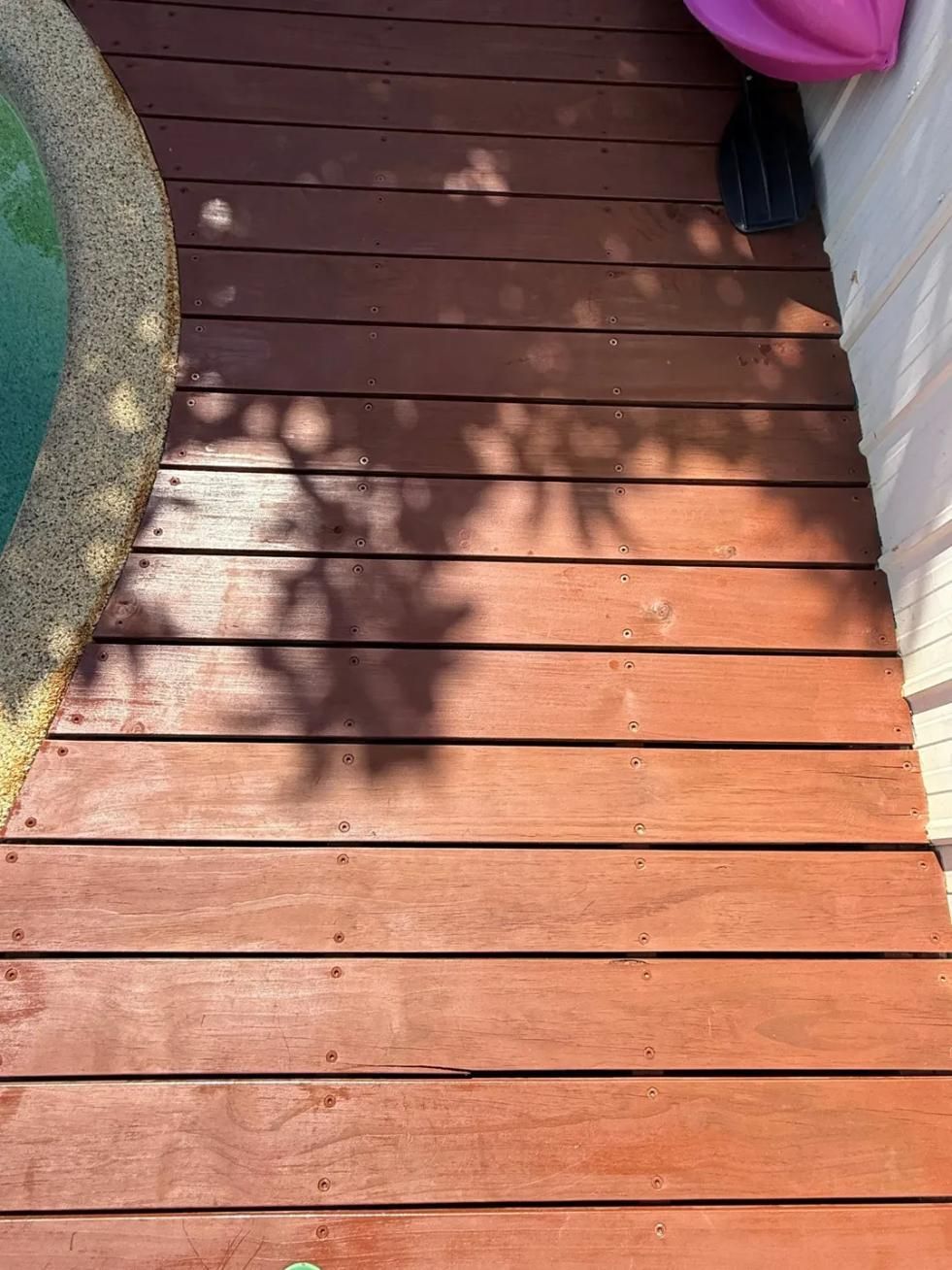 A Wooden Deck Next to a Pool With a Shadow of a Tree on It — Central Coast Property Maintenance Services In Umina Beach, NSW