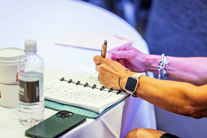 a woman wearing an apple watch is writing in a notebook