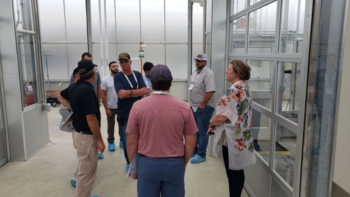a group of people standing in a room with an exit sign above them
