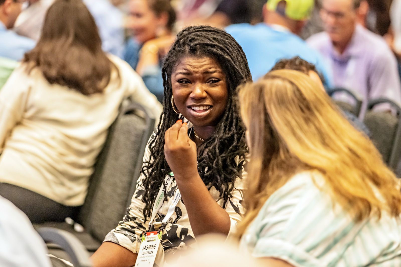 a group of people are sitting in chairs talking to each other .