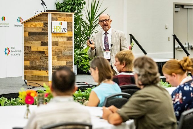 a man stands in front of a podium that says thrive