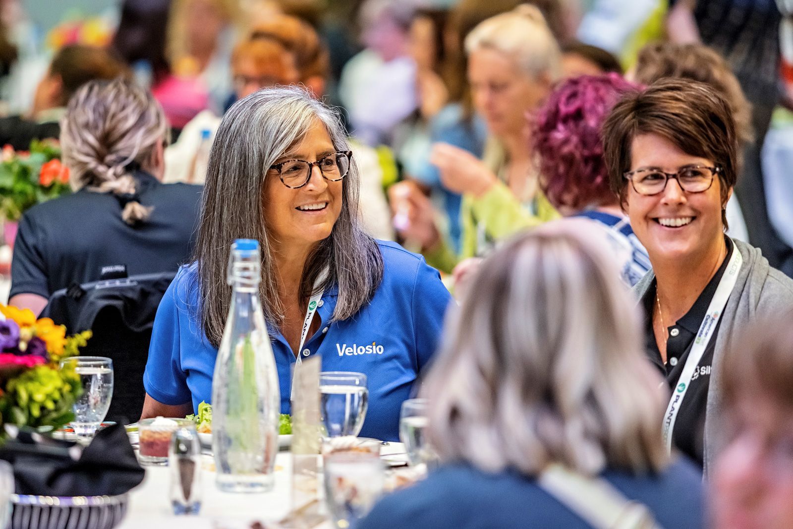 a group of women are sitting at a table talking to each other .