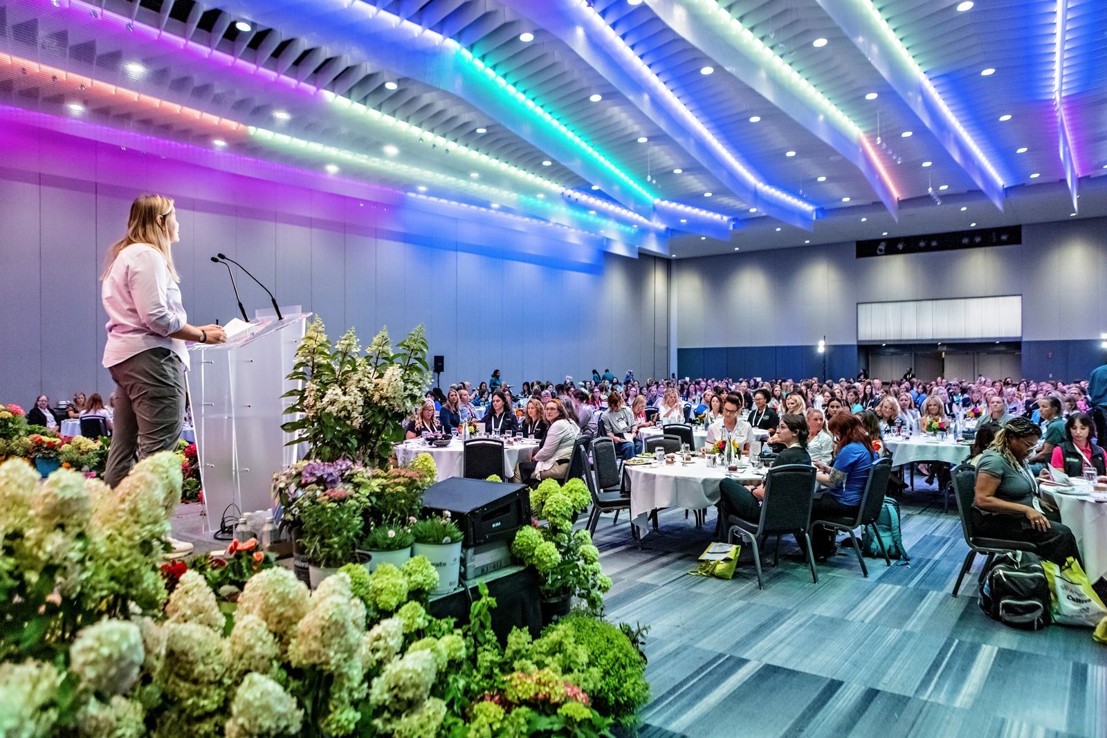 a woman is standing at a podium giving a speech in front of a large crowd .
