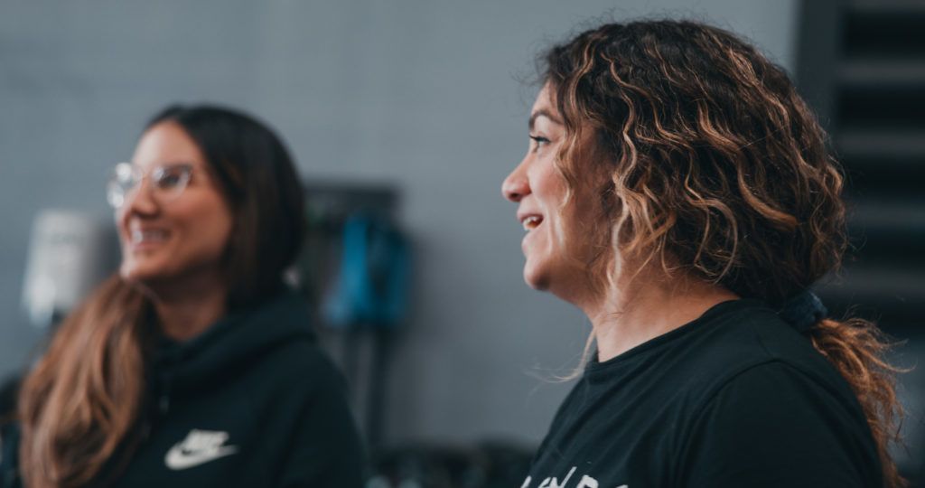 Two women are sitting next to each other in a room and smiling.