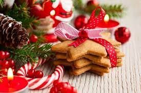 A stack of gingerbread cookies with a red ribbon on a table with christmas decorations.