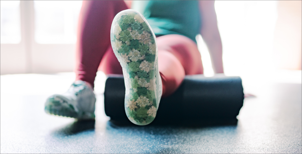 A woman is stretching her leg on a foam roller.