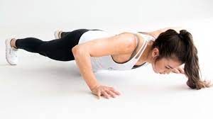 A woman is doing push ups on a white surface.