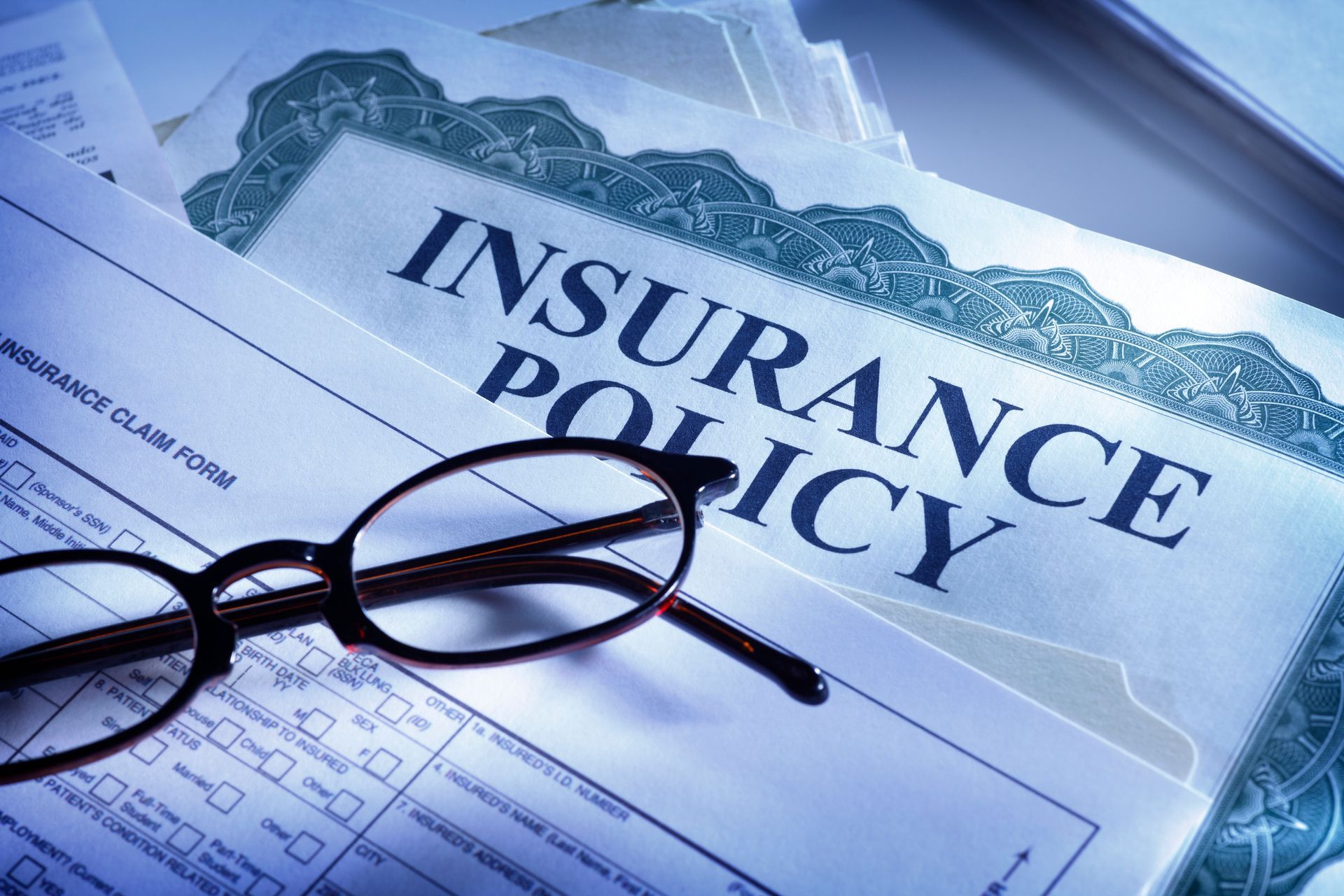 Close-up of an insurance policy document with eyeglasses, emphasizing business insurance coverage in