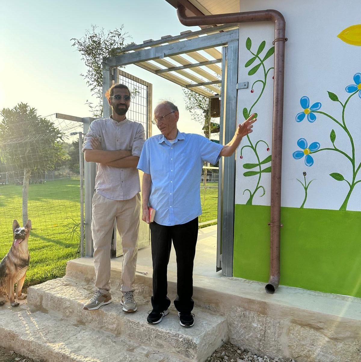 Due uomini in piedi davanti a un edificio con fiori dipinti sul muro