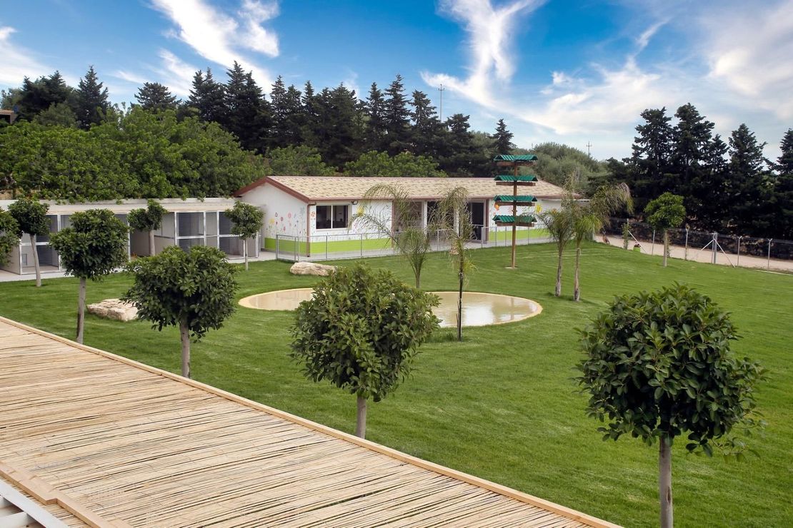 Un lussureggiante campo verde con alberi e una casa sullo sfondo