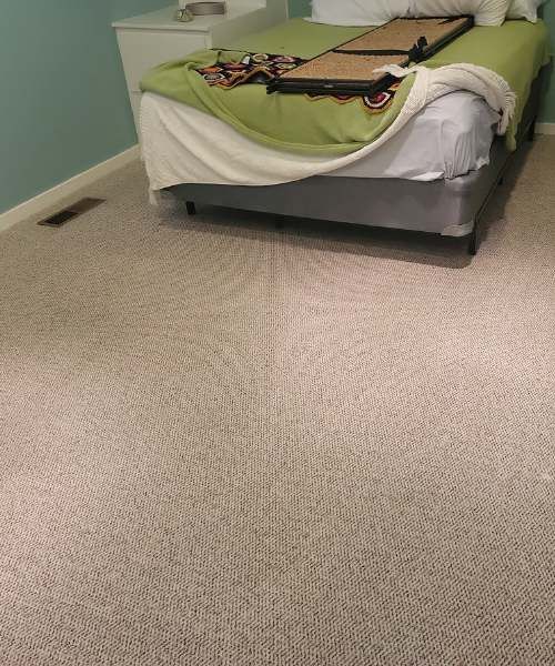 A bedroom with a bed and a carpeted floor