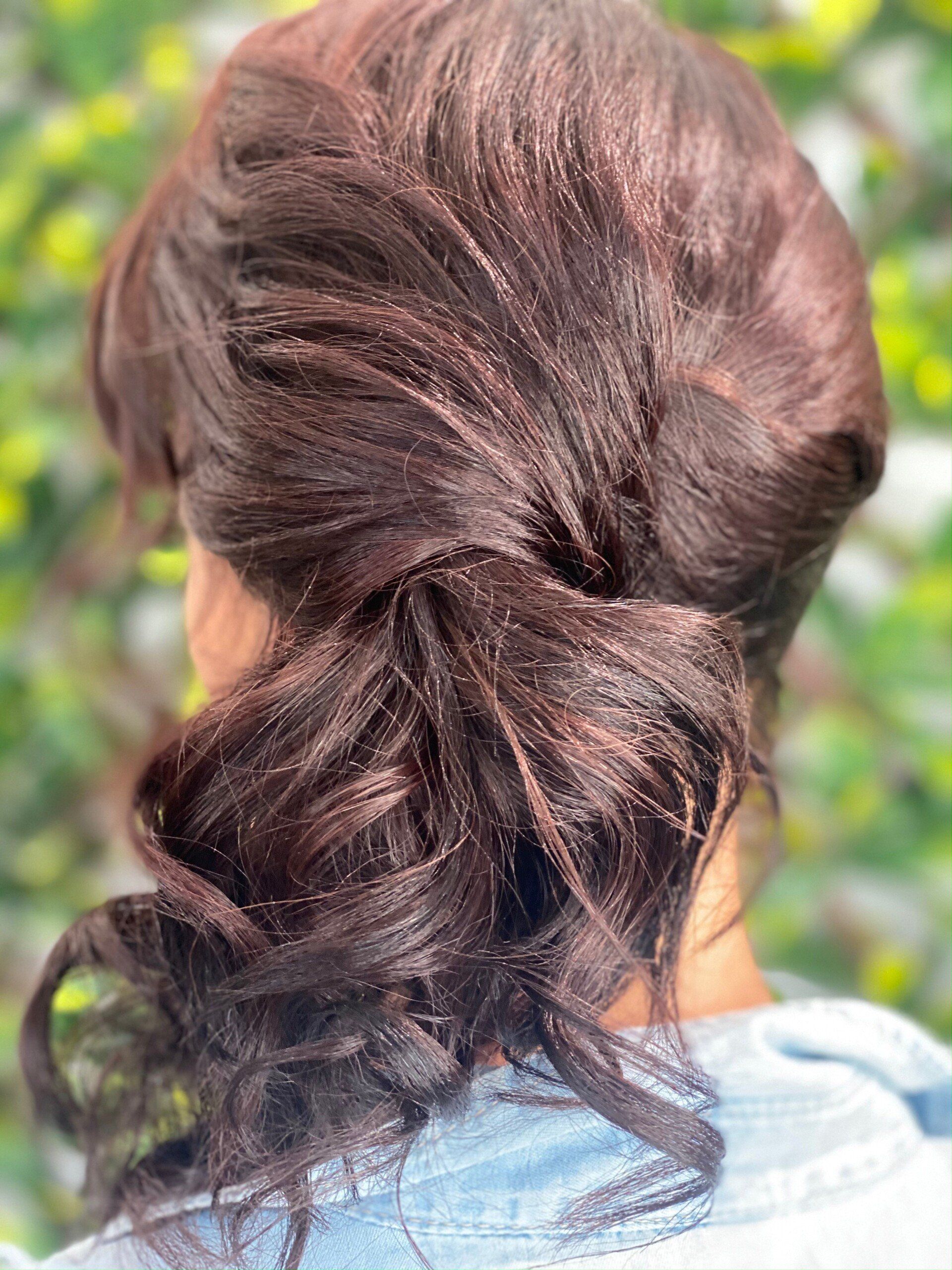 Woman with dark brown hair in a low, side bun.