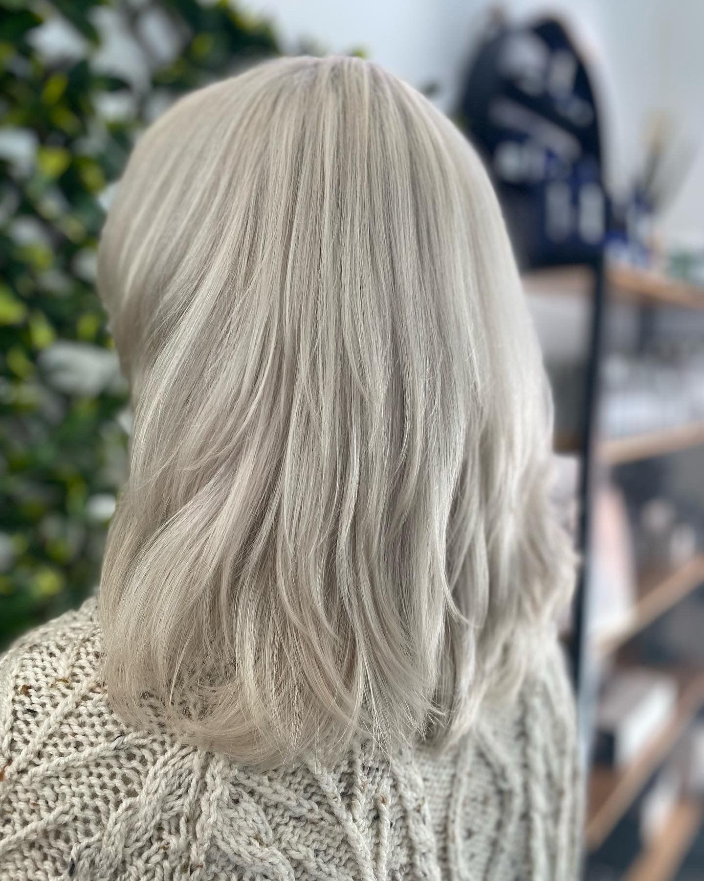 A woman with white hair is wearing a white sweater.