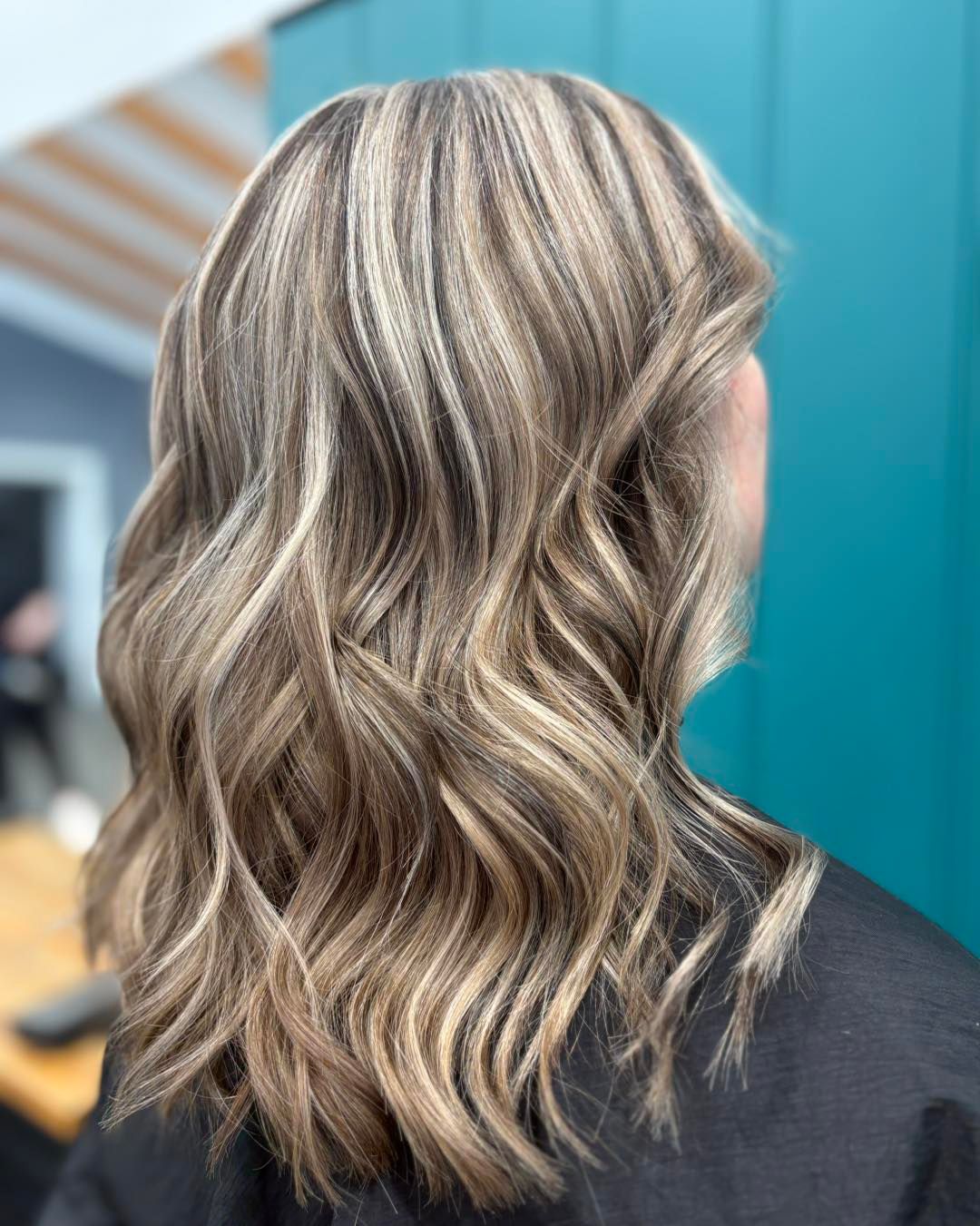 Woman with wavy, highlighted hair in shades of blonde and brown.