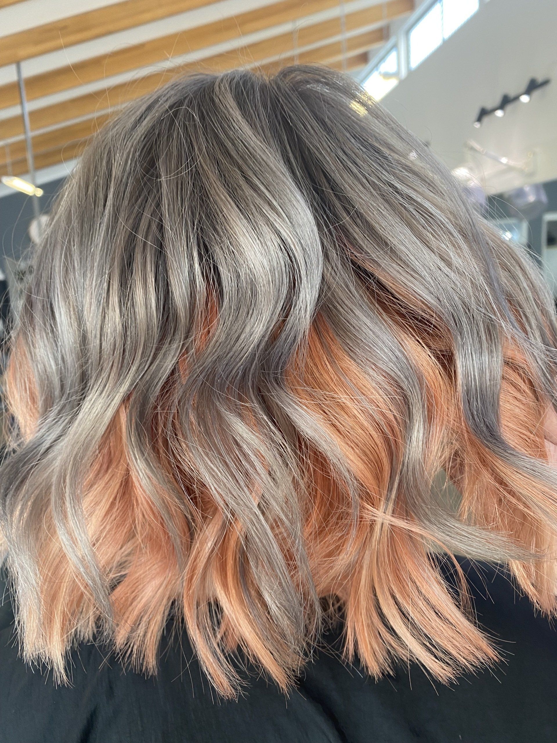 Woman with gray hair and peach-colored ends, wavy style.