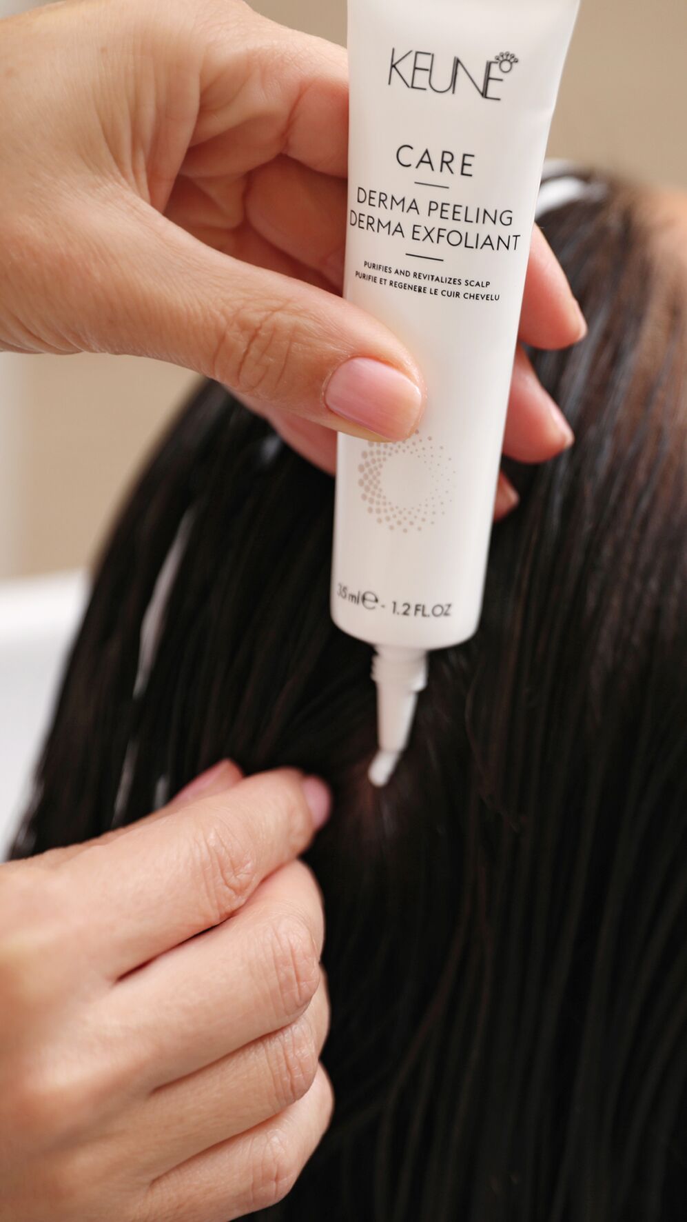 Hand applying Keune Derma Peeling product to a person's scalp, in a salon setting.
