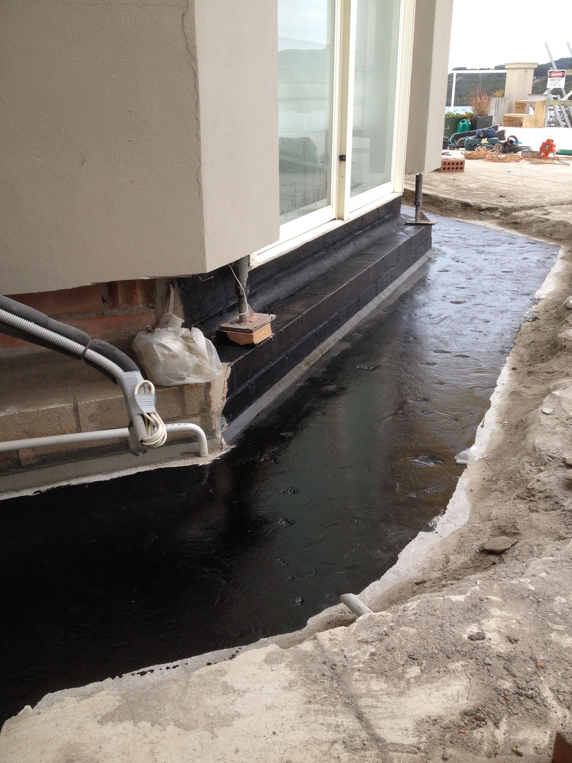 A Close Up Of A New Paved And Waterproofed Base To Prevent Brick Damage — Heritage Bricklaying & Remedial Services In Jilliby, NSW