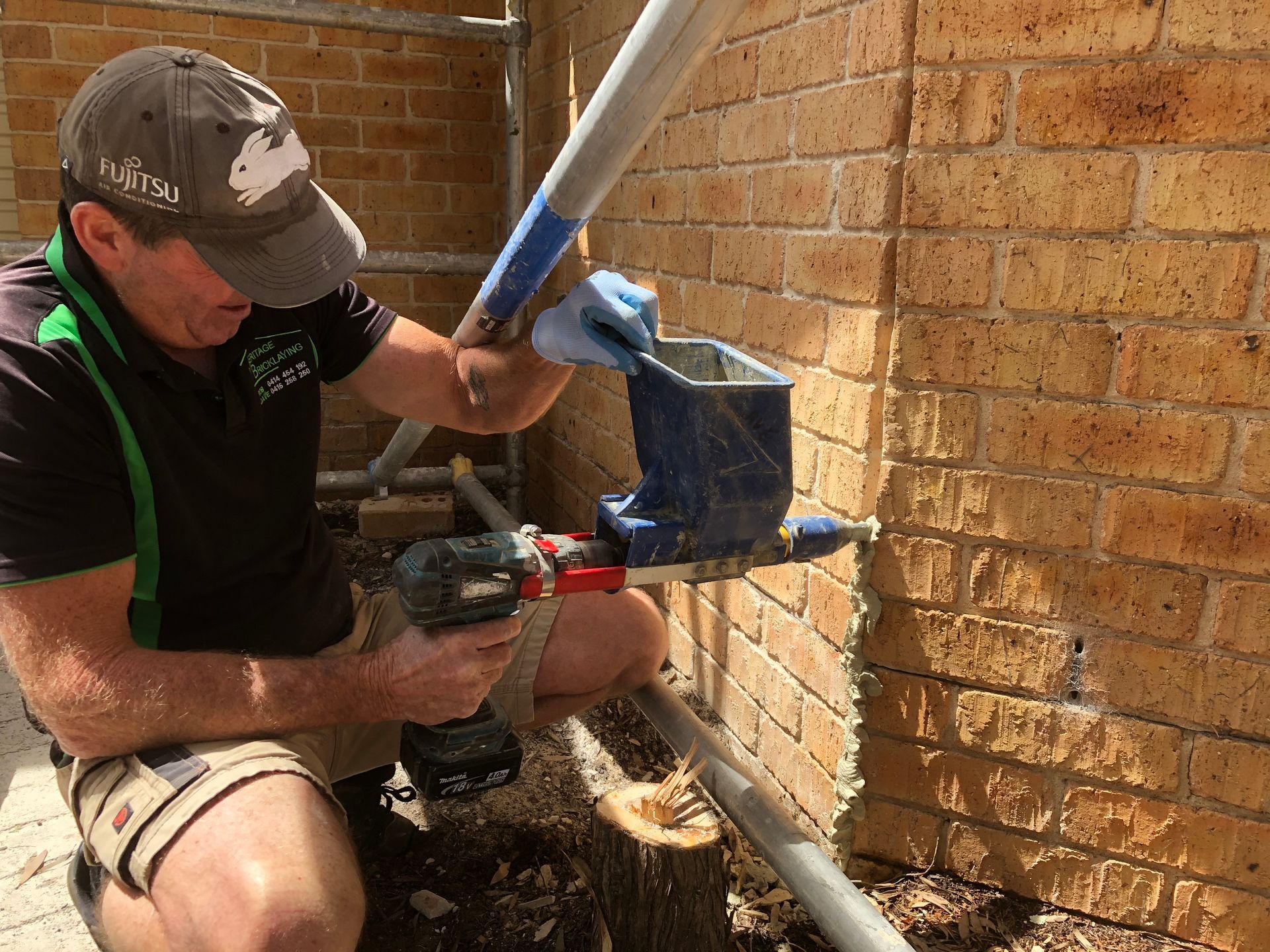 A Man Is Fixing A Brick Wall — Heritage Bricklaying & Remedial Services In Jilliby, NSW