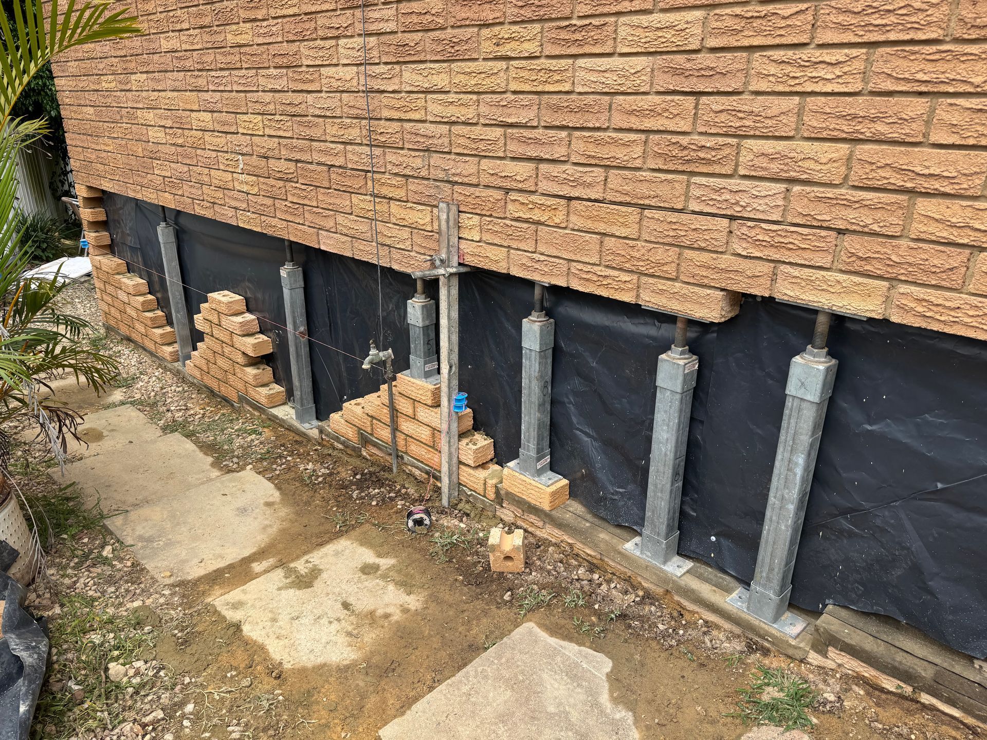 A Brick Wall Fixing In Progress With Metal Bracing Wolding the Bricks In Prep For New Bricks — Heritage Bricklaying & Remedial Services In Jilliby, NSW