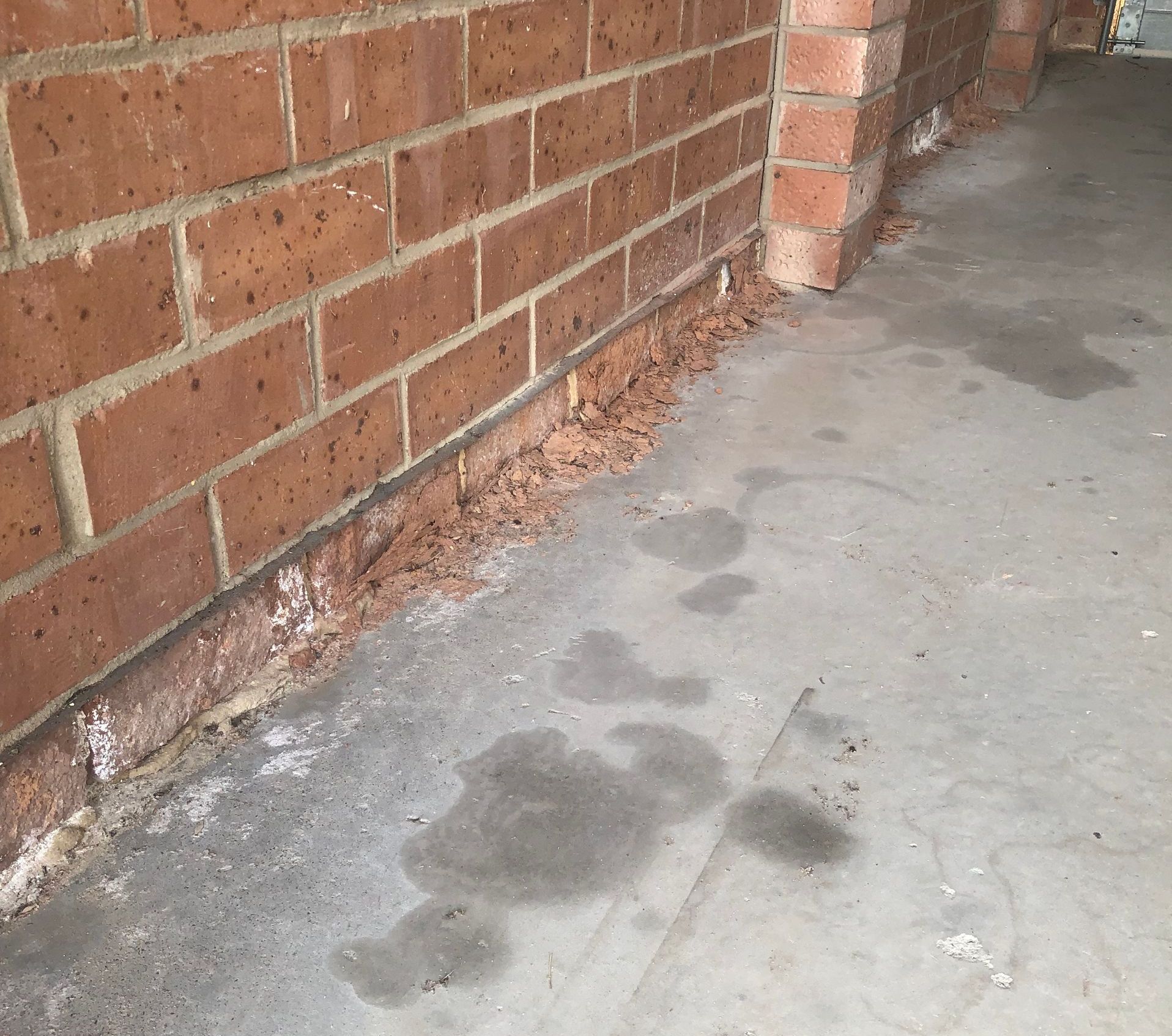A Brick Wall With Holes In It Is Sitting In The Grass — Heritage Bricklaying & Remedial Services In Jilliby, NSW