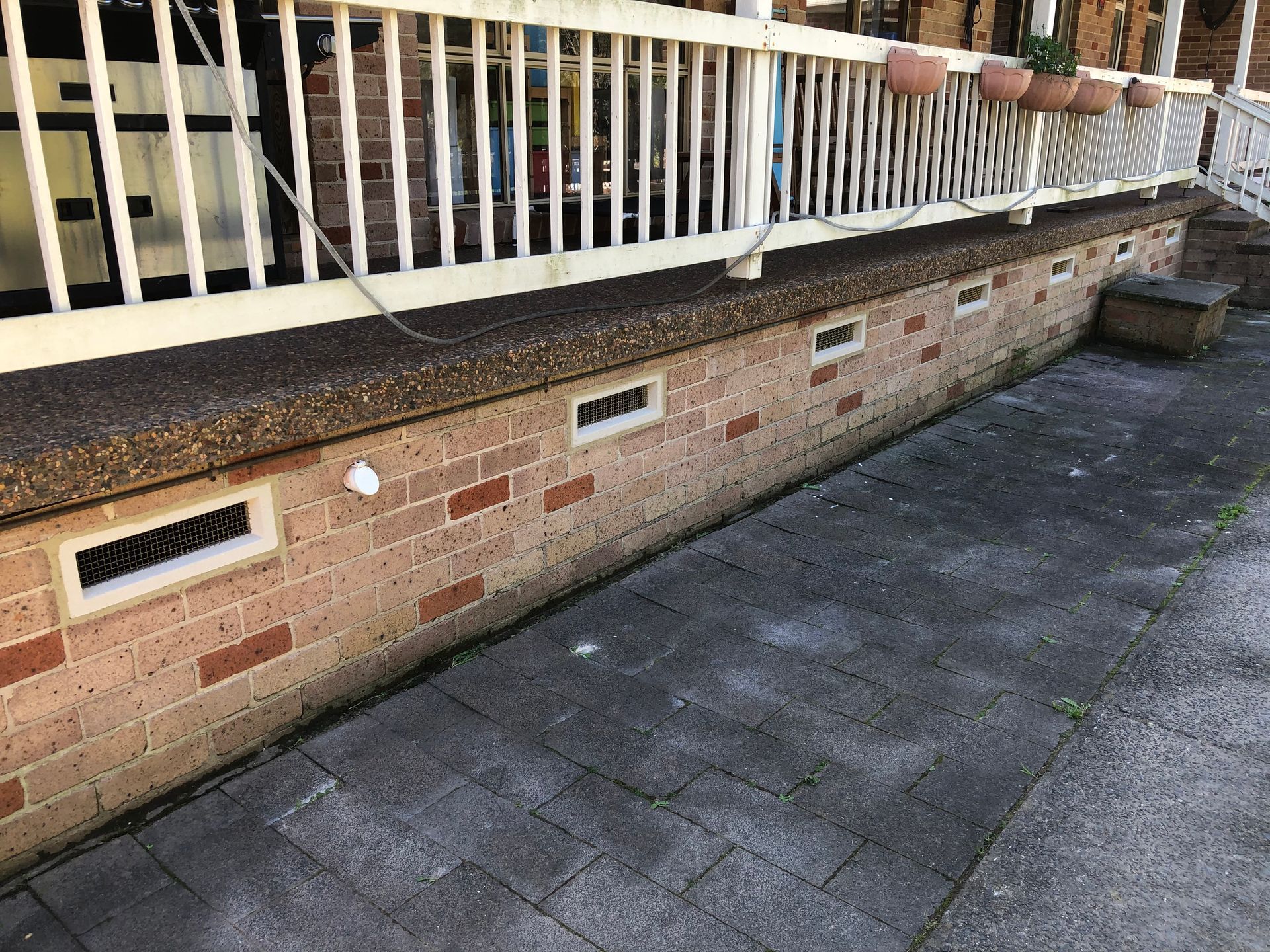 A Brick House With A Concrete Patio In Front Of It — Heritage Bricklaying & Remedial Services In Jilliby, NSW