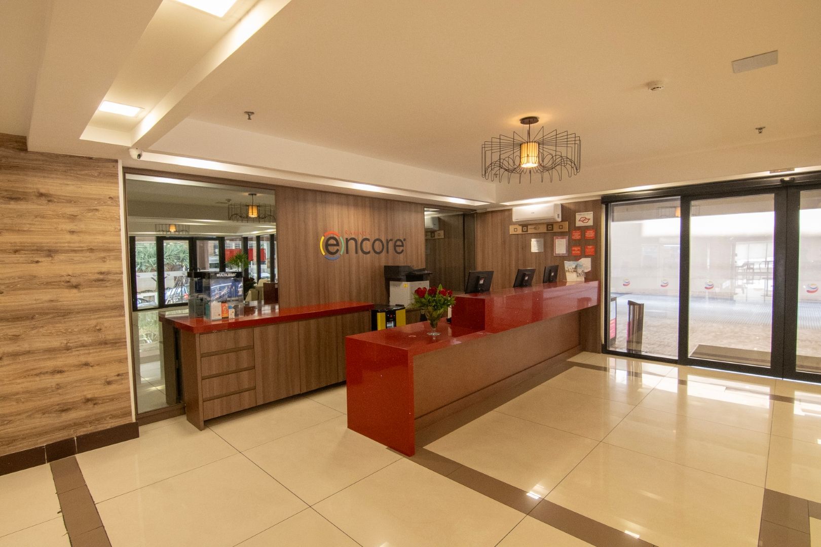 Um lobby de hotel com um balcão vermelho e uma grande janela.