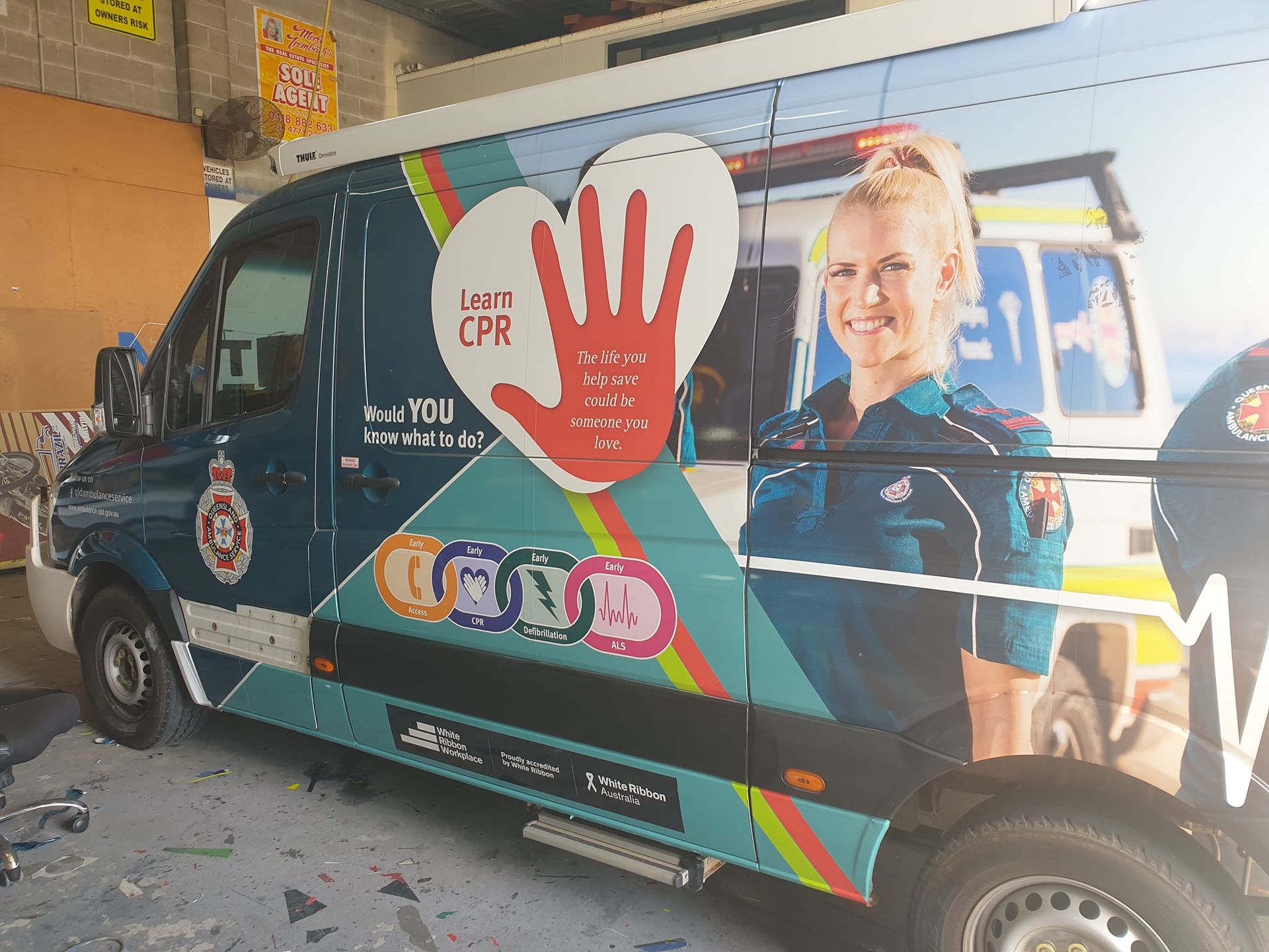An ambulance with a picture of a woman on the side is parked in a garage.