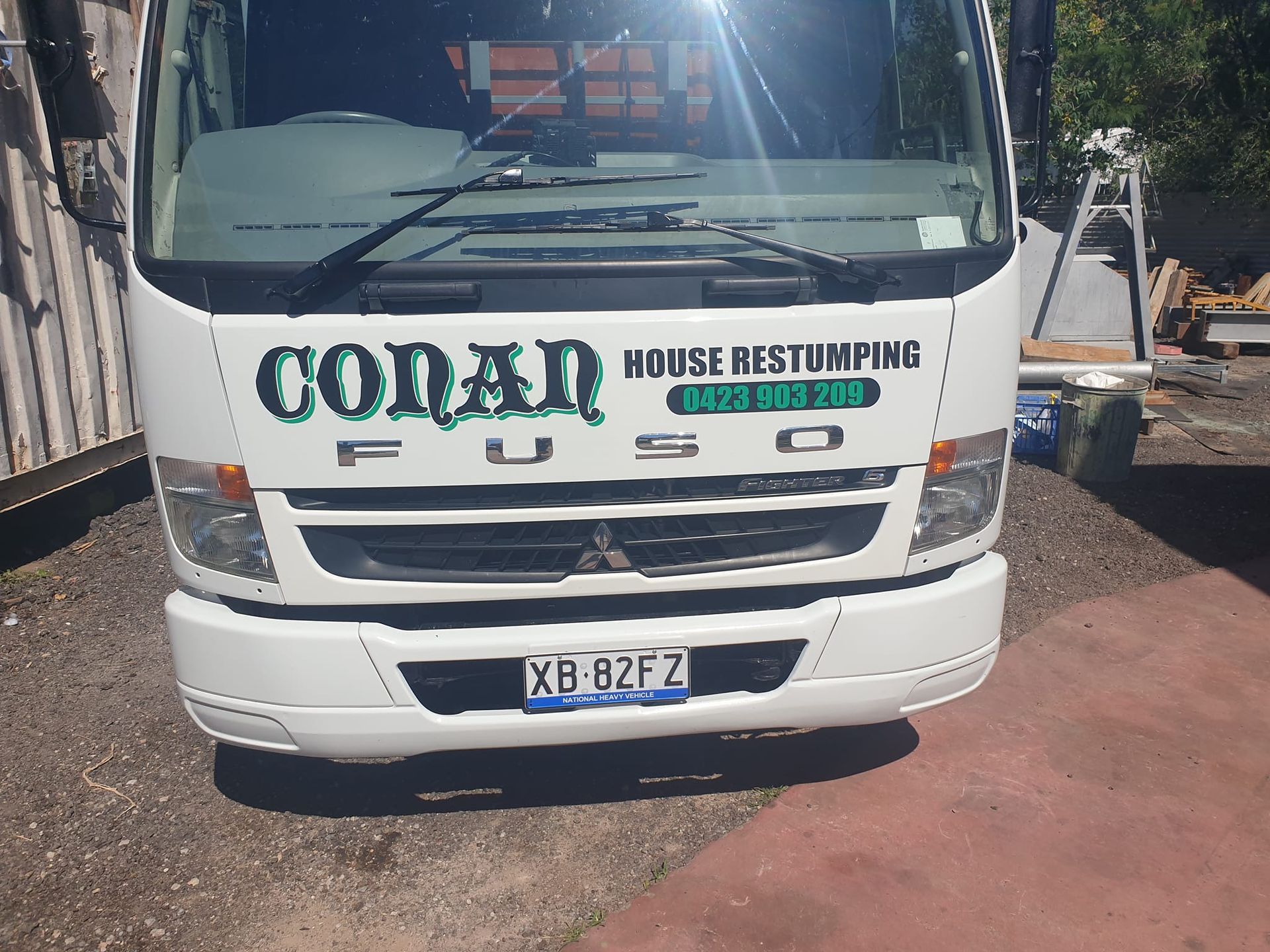 A white truck with the word conan on the front is parked in a driveway.