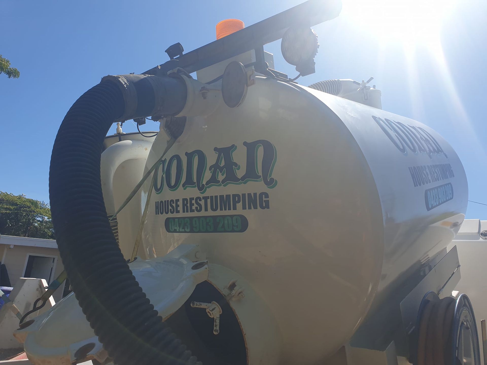 The back of a vacuum truck with a hose attached to it.