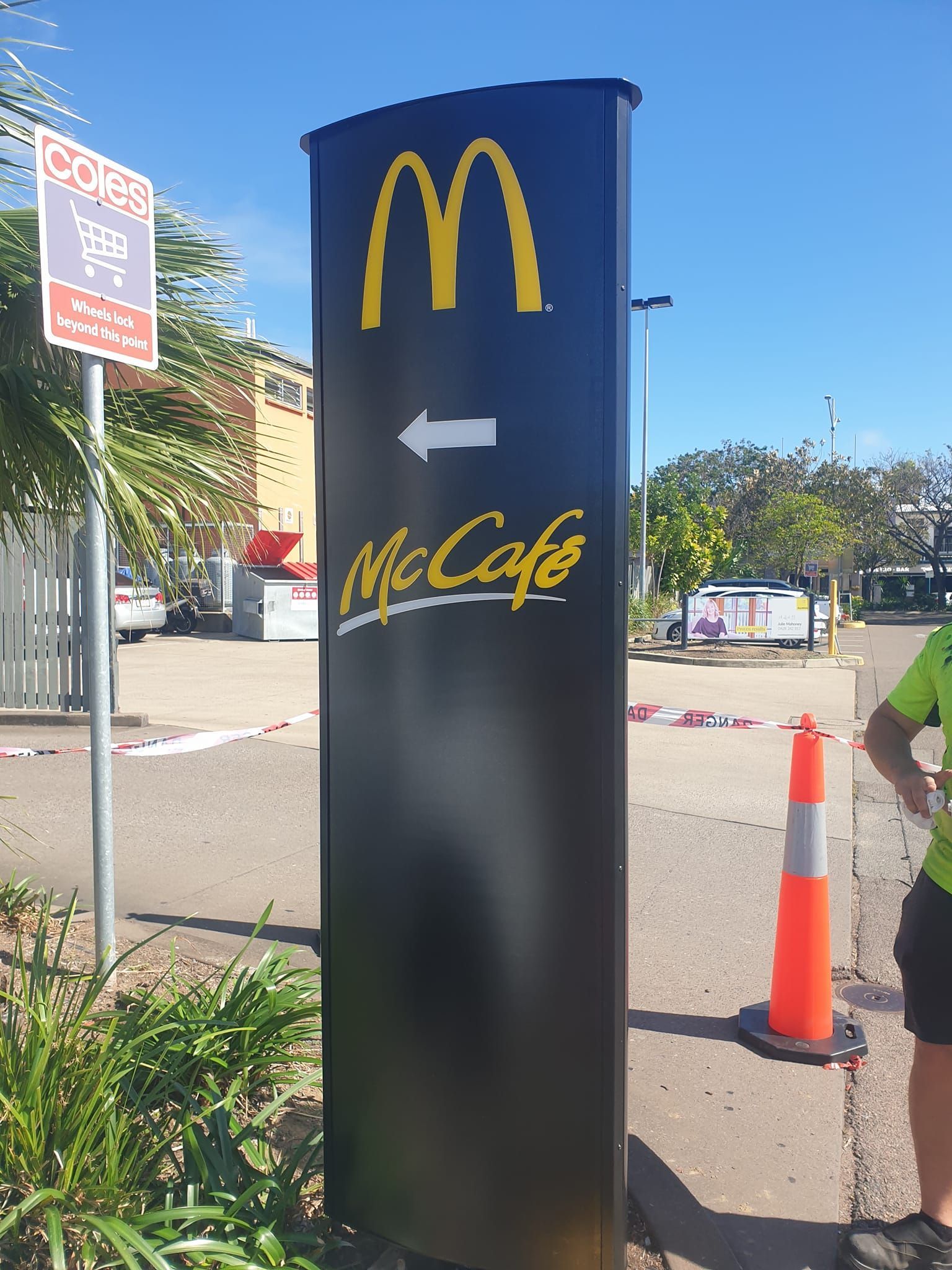 A man is standing next to a mcdonald 's sign.
