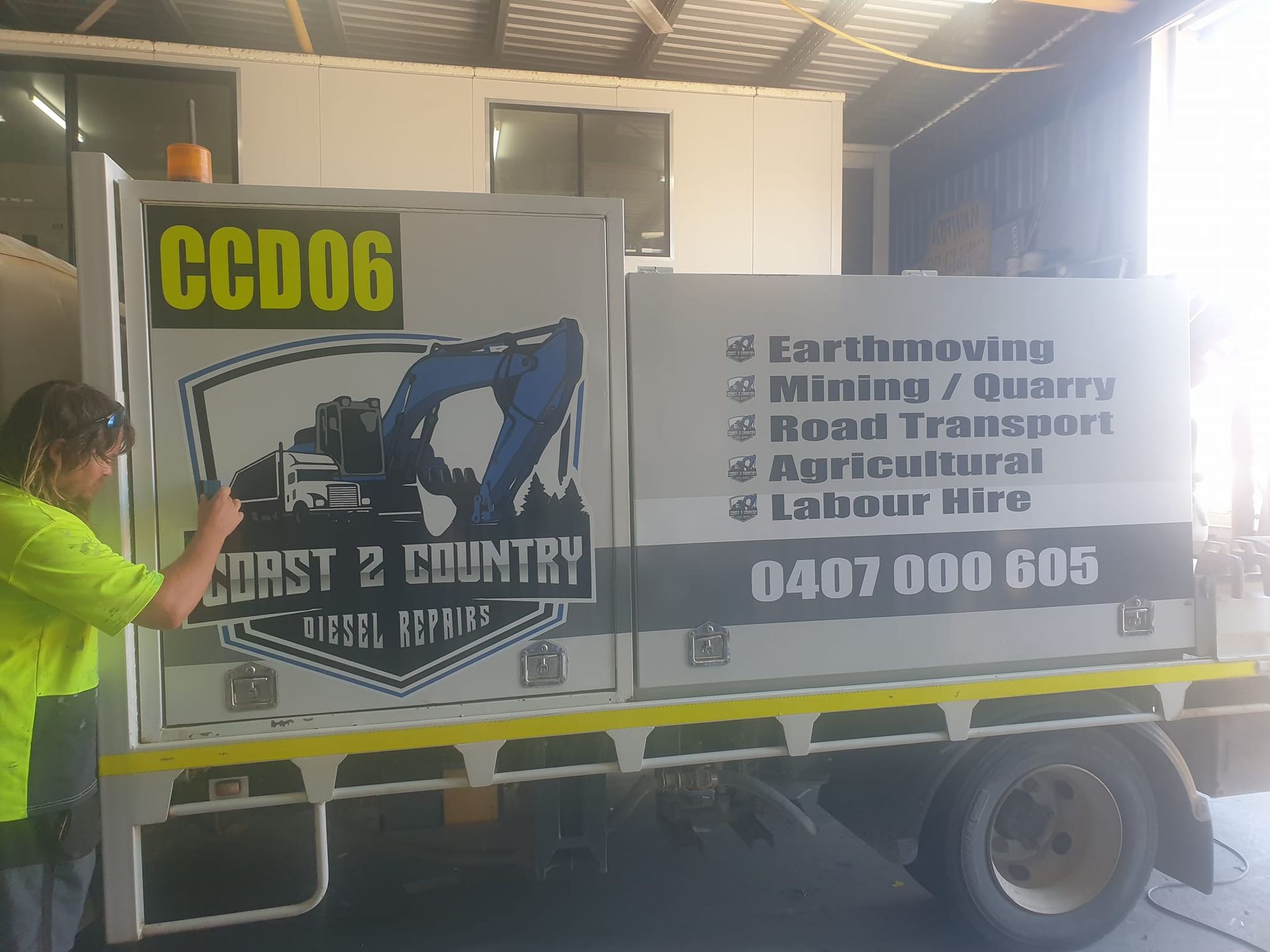 A woman is putting a sign on the side of a truck.