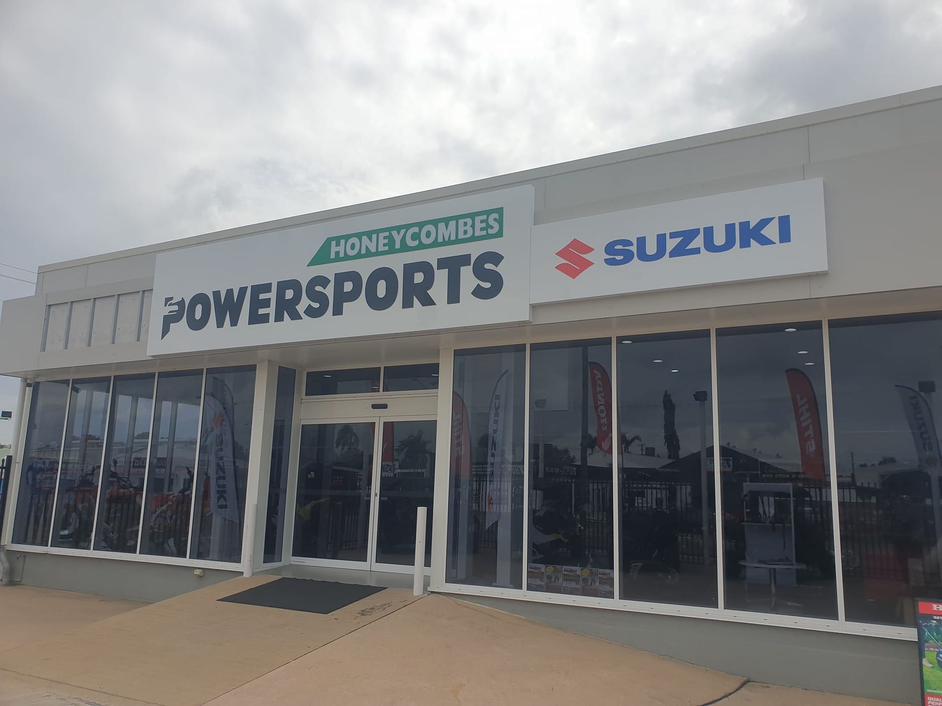The front of a suzuki powersports store with a sign on it.