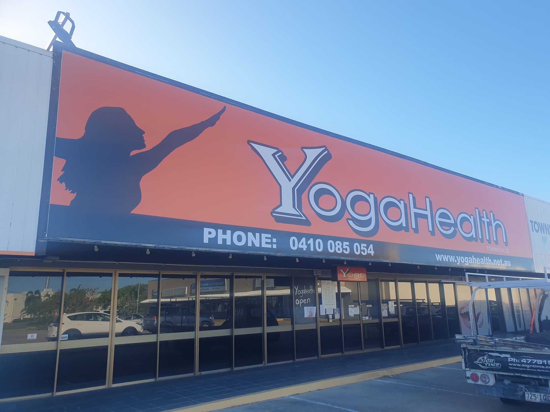 A building with a large orange sign that says yoga health