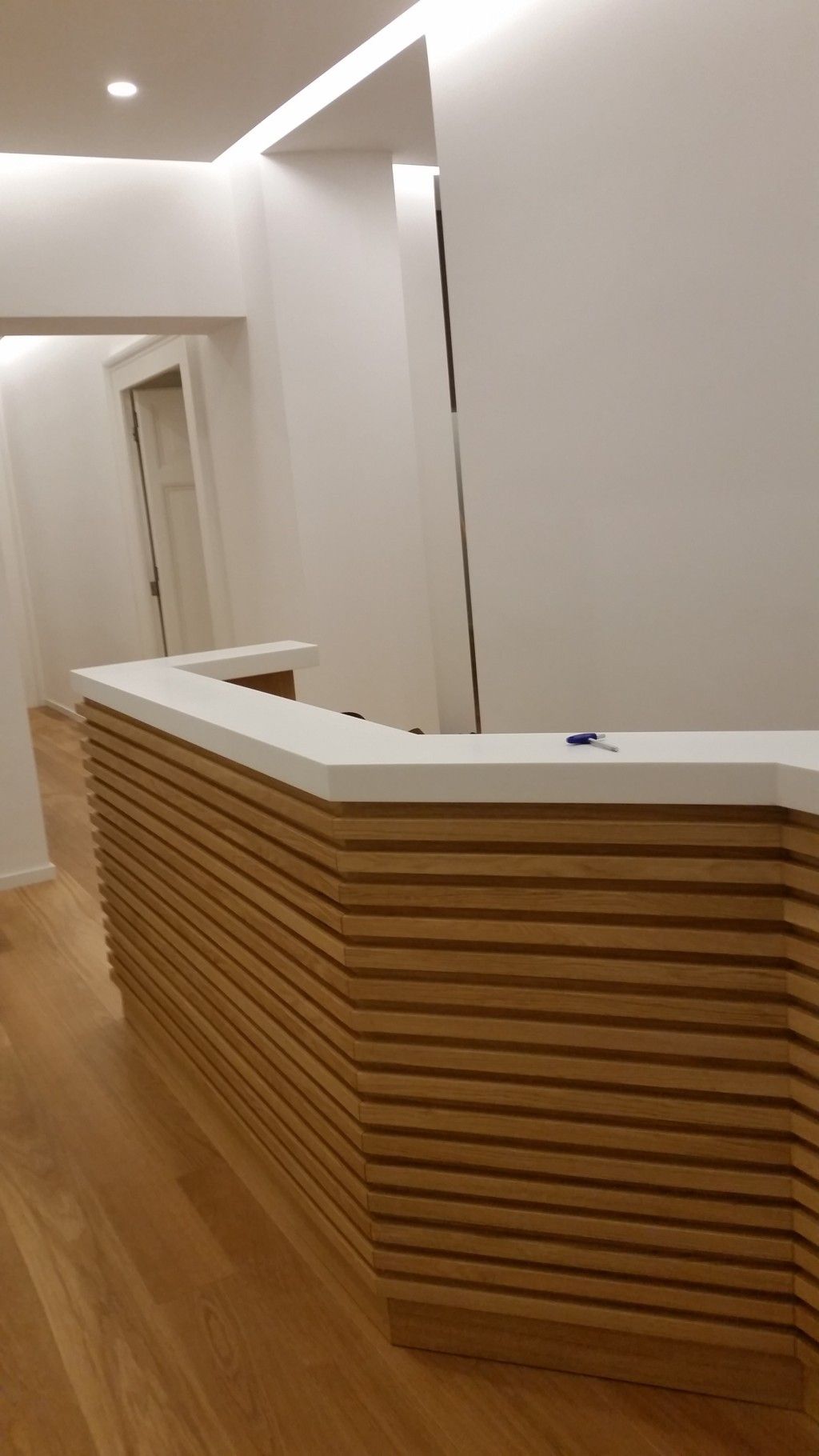 Banco reception moderno con piano bianco e listelli in legno in un corridoio pulito